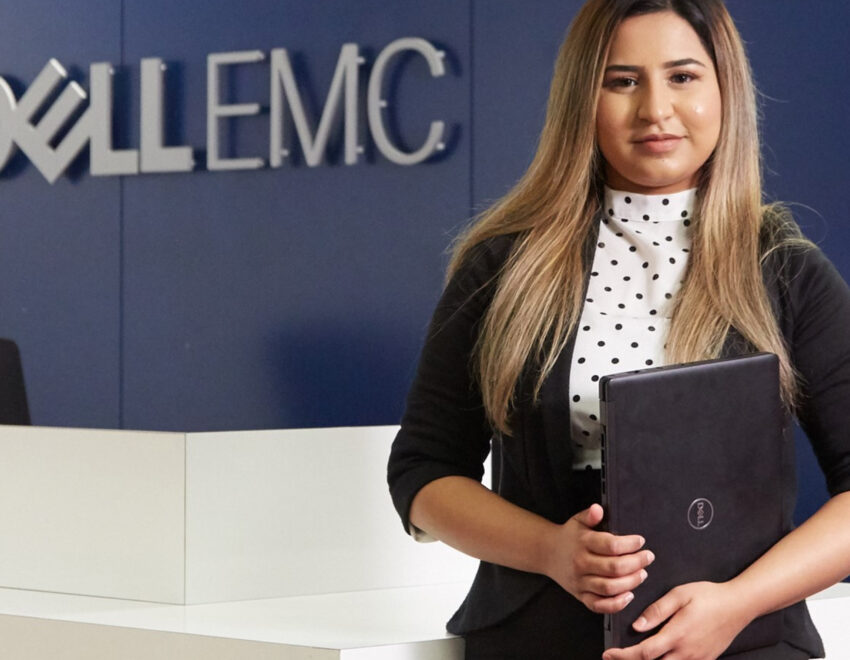 Young Apprenticeship standing in front of DellEMC signage