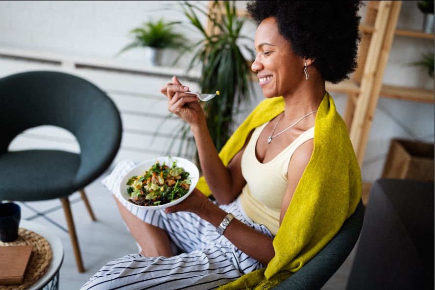 Woman enjoying eating a bowl of vegetable salad