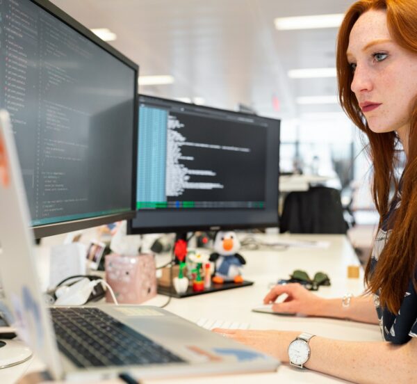 Woman concentrating on three desktop computer screens
