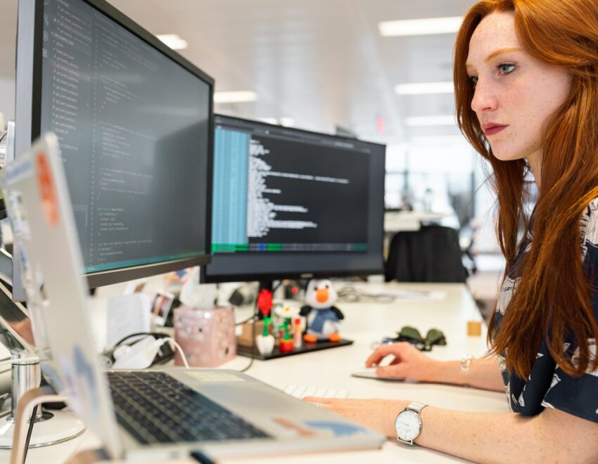 Woman concentrating on three desktop computer screens