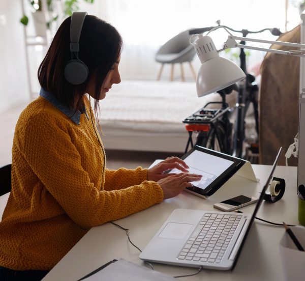Woman working at home at a laptop while on the phone. Links to flexible working