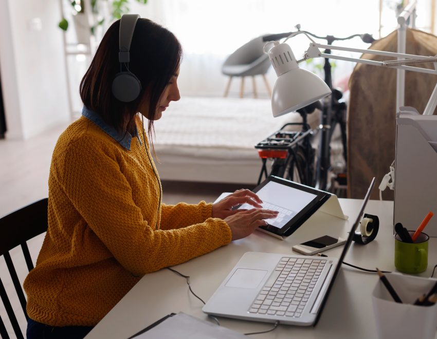 Woman working at home at a laptop while on the phone. Links to flexible working