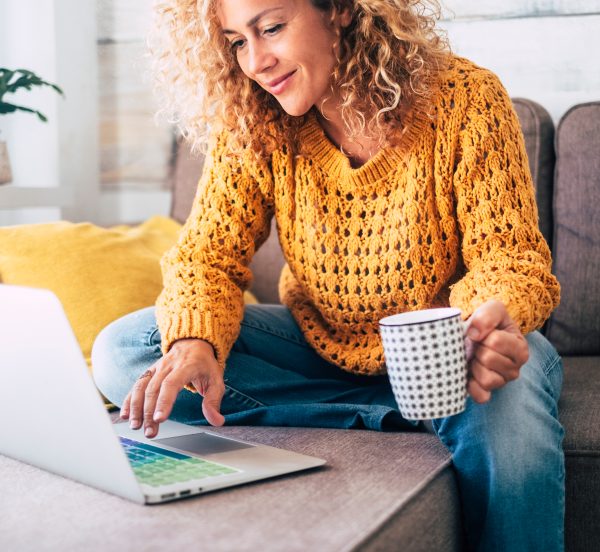 Smiling woman drinking coffee sat at a laptop