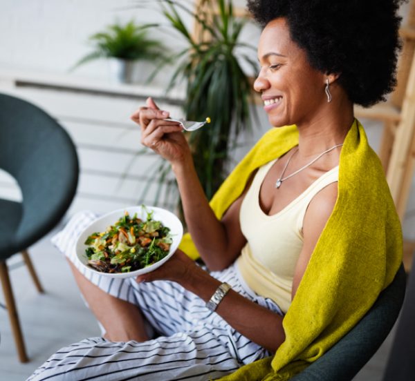 Woman enjoying eating a bowl of vegetable salad