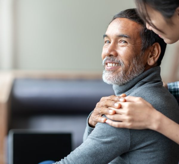 Smiling older man touching carers hand