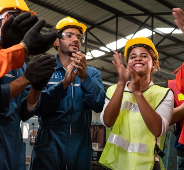 A man and a woman wearing hard hats and applauding