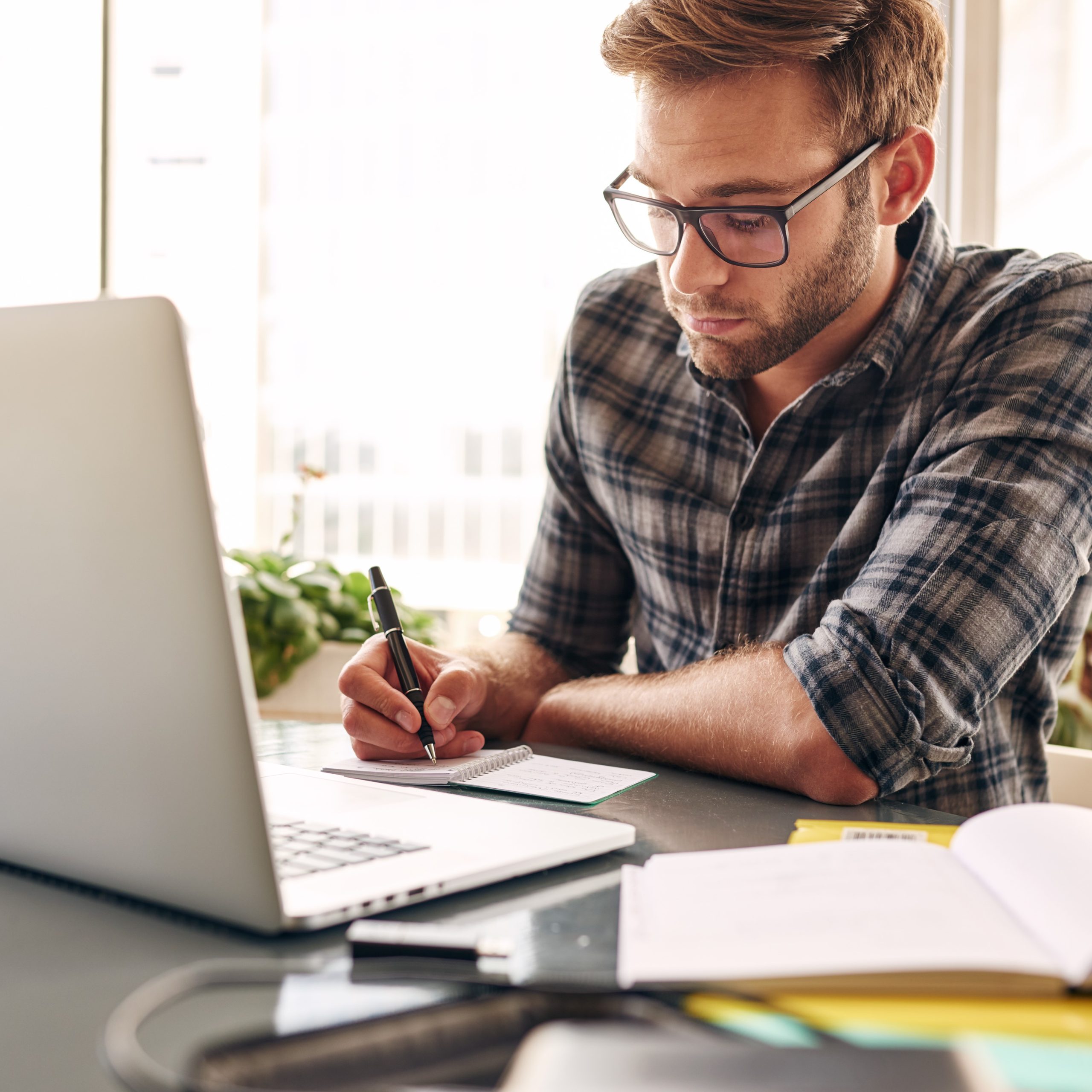 Man in front of a laptop taking notes